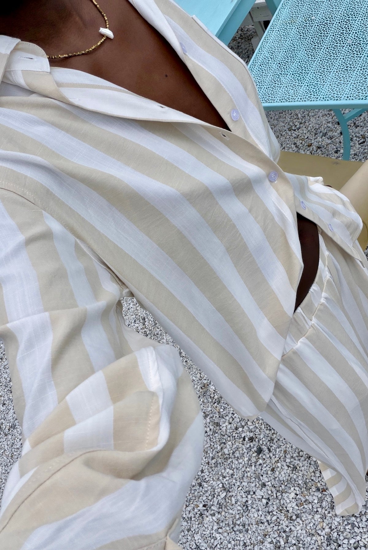 Close-up of a person wearing a white and beige striped shirt on a textured surface.