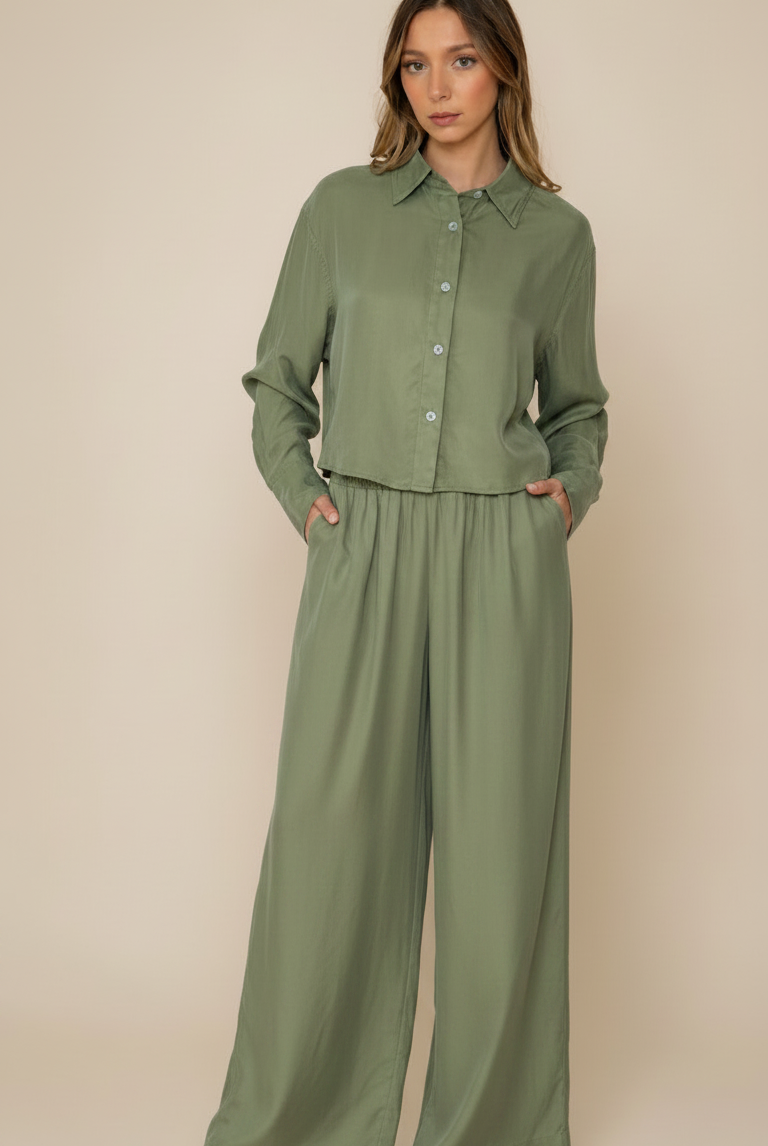 Woman wearing a green outfit with wide-leg pants on a beige background