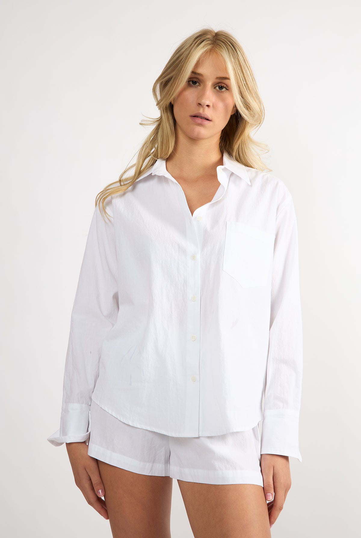 Woman wearing a white shirt and shorts on a plain background