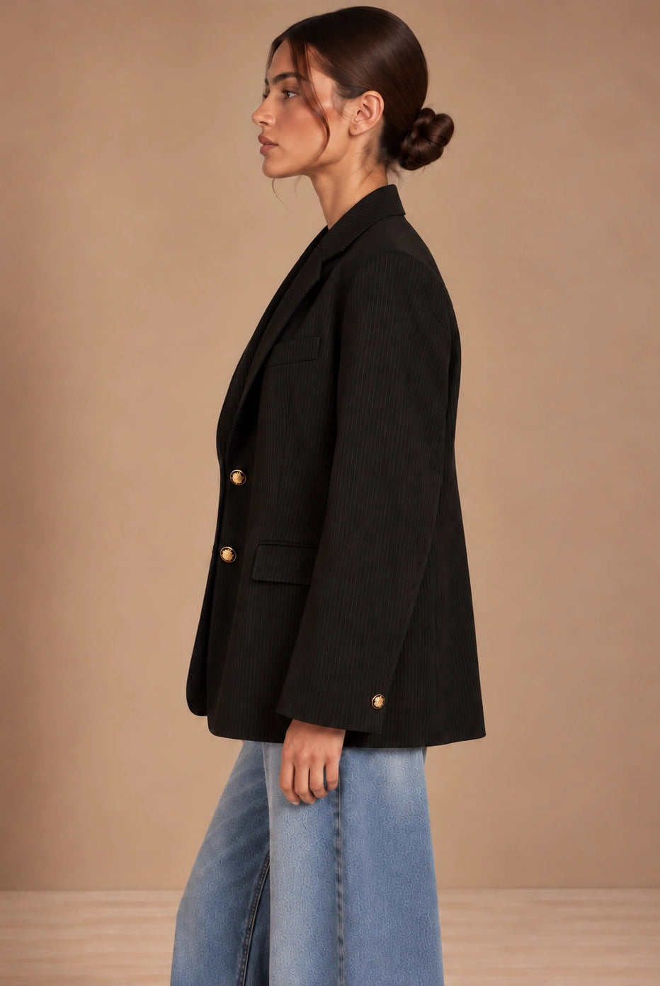 Side profile of oversized black pinstripe blazer with gold cuff button