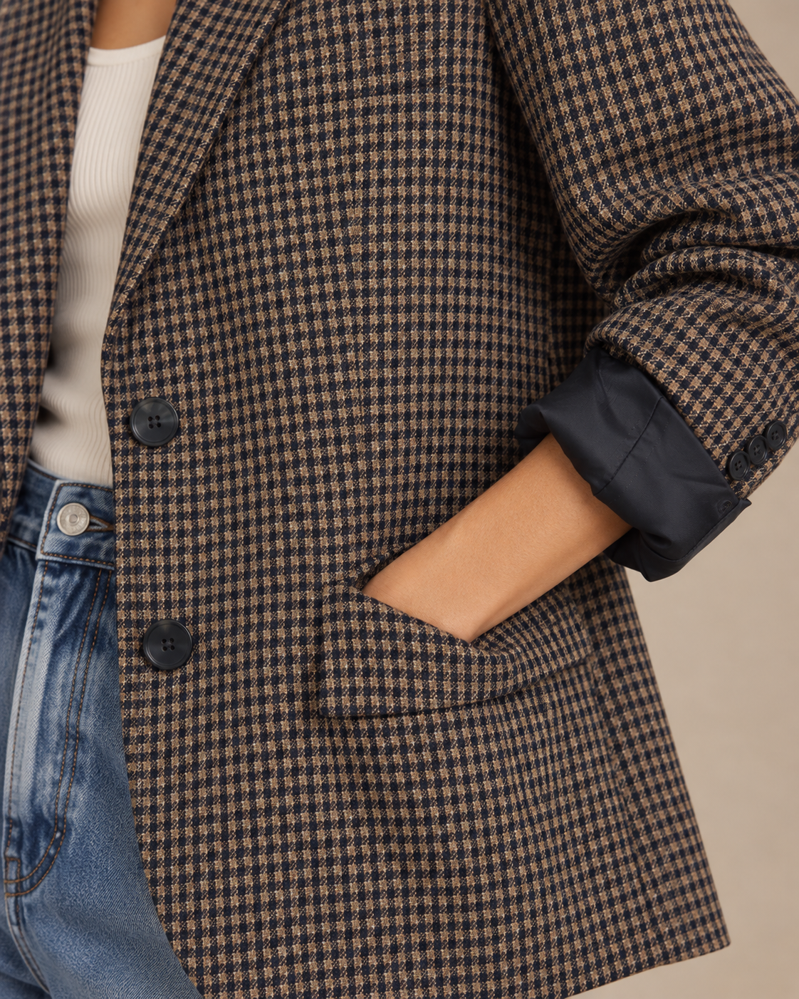 Close-up of navy and camel check blazer with flap pocket, buttons and rolled navy-lined cuff