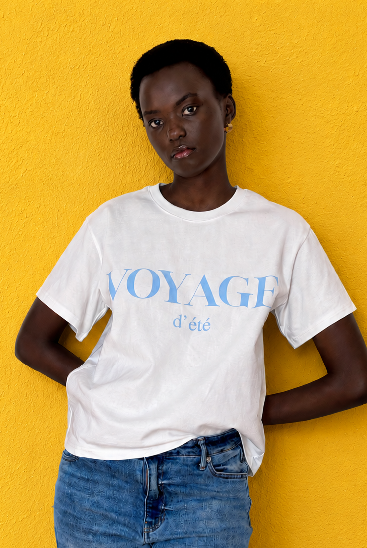 Model wearing boxy tee which reads Voyage d'Ete in blue on a white t-shirt