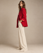 Side view of red double-breasted blazer with cream trousers and pointed flats