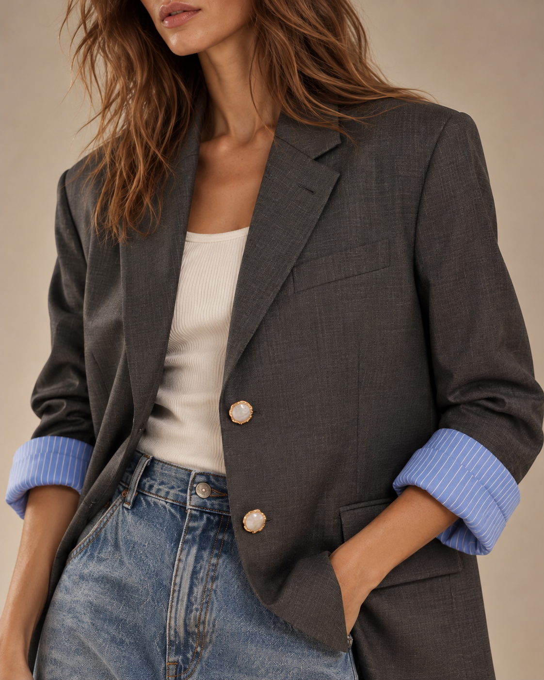 Close-up of charcoal blazer with gold pearlescent buttons and blue striped rolled cuffs