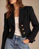 Close-up of peak lapels, topstitching and gold crest buttons on vintage black blazer