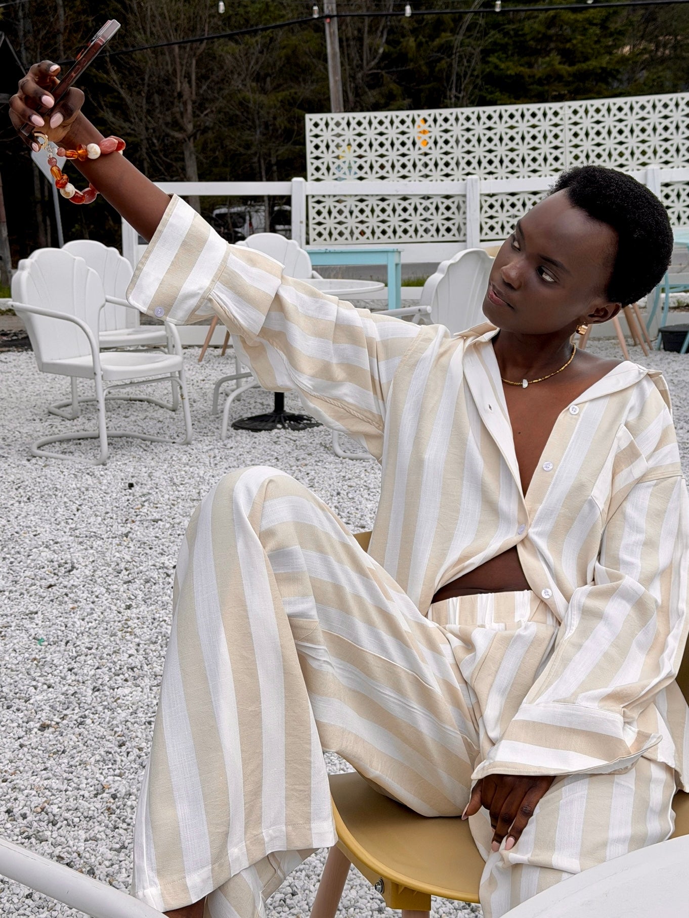 woman sitting taking a selfie in the beige stripe set 