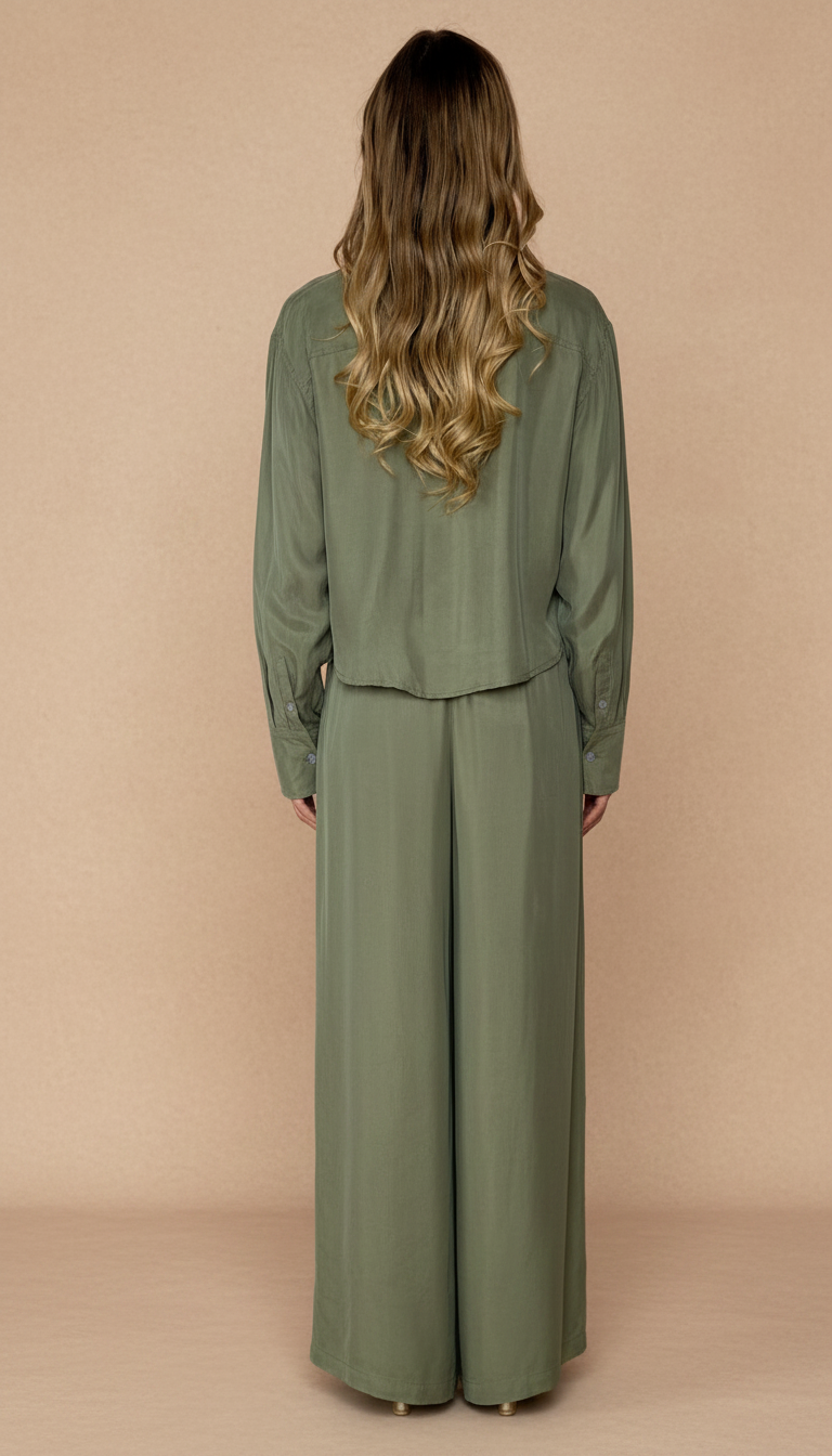 Woman wearing a green outfit with wide-leg pants against a beige background