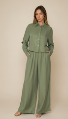 Woman wearing a green outfit with wide-leg pants on a beige background
