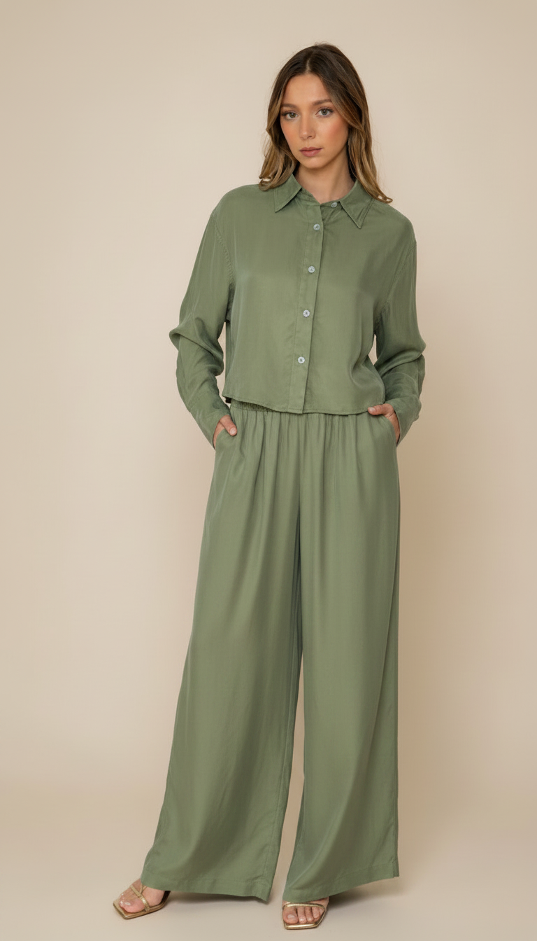 Woman wearing a green outfit with wide-leg pants on a beige background