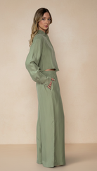 Woman wearing a matching green outfit against a beige background