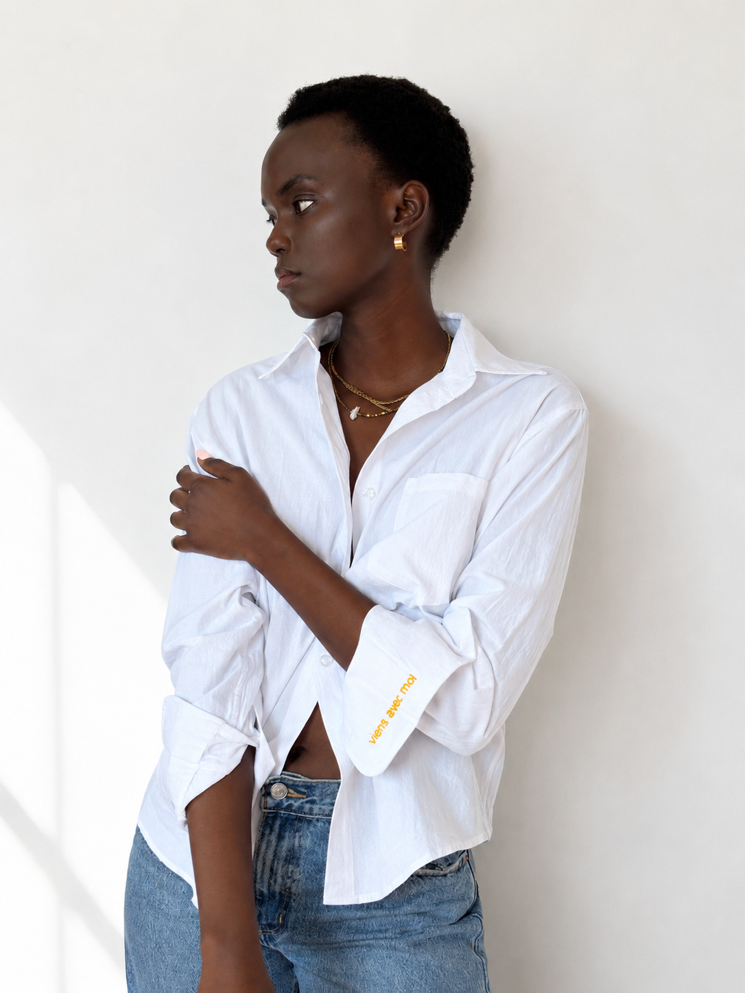 White embroidered cotton Everyday Boyfriend Shirt with "viens avec moi" cuff detail, worn by a model.