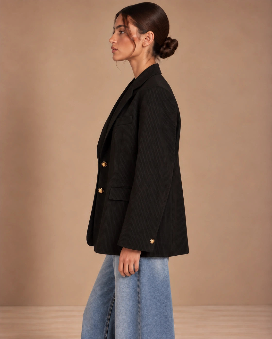 Side profile of oversized black pinstripe blazer with gold cuff button