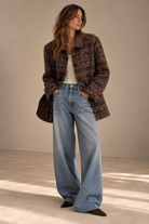 Woman wearing vintage brown and rust geometric jacquard coat with wide-leg jeans, front view