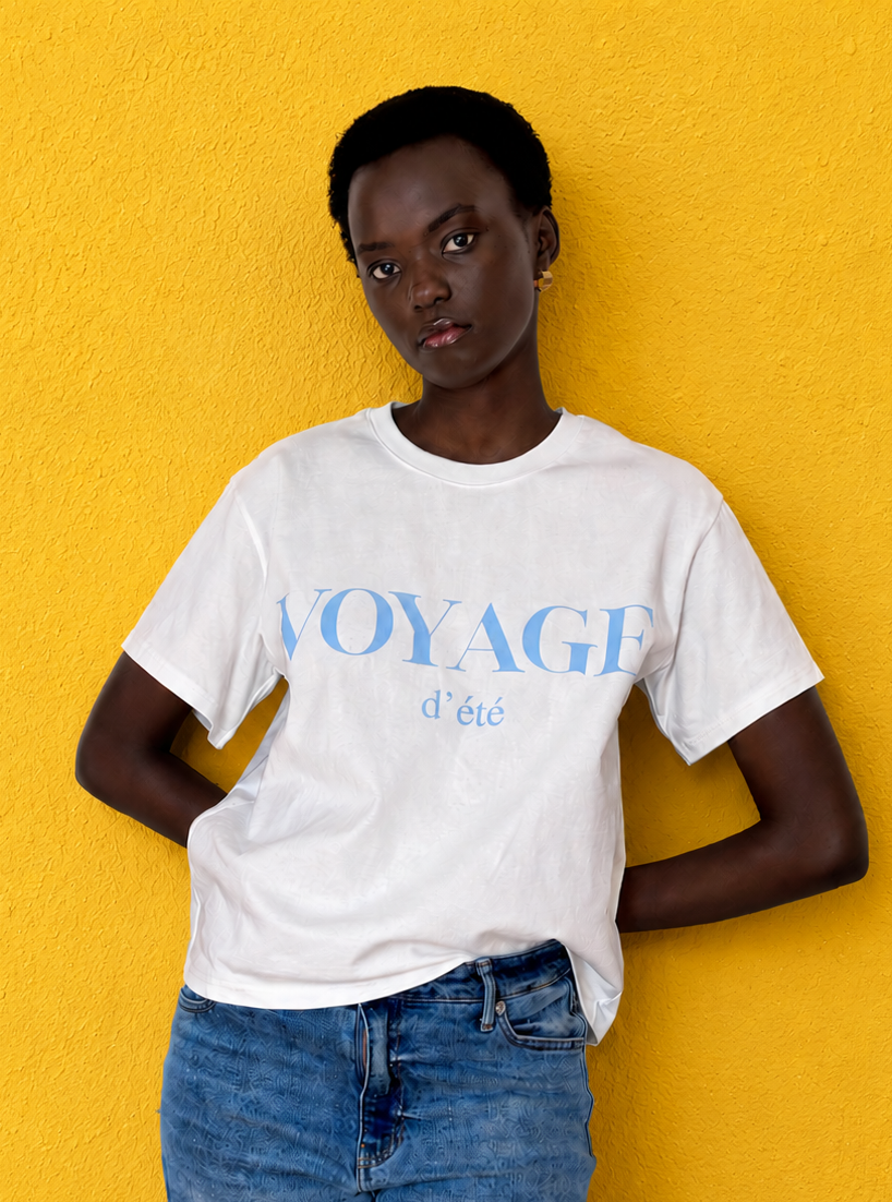 Model wearing boxy tee which reads Voyage d'Ete in blue on a white t-shirt